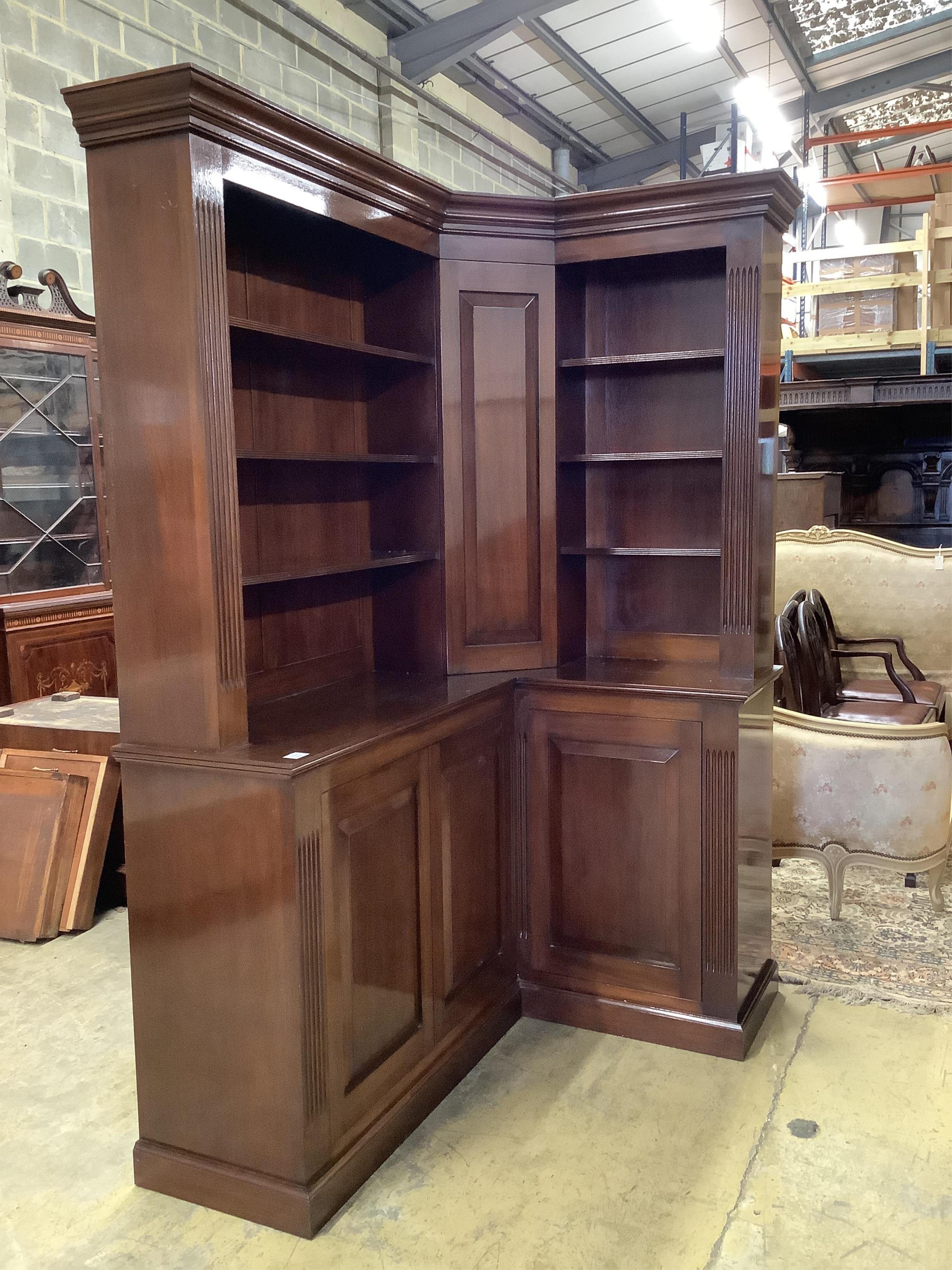 A George III style mahogany corner library bookcase, the mid section incorporating a secret cupboard, width 142cm, depth 102cm, height 213cm. Condition - good